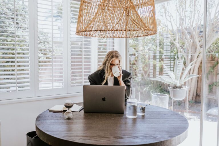 woman drinking coffee working on laptop